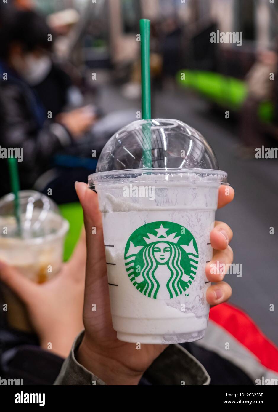 Ragazza che tiene e beve bevande Starbucks, Kyoto, Giappone in un treno pendolari. Foto Stock
