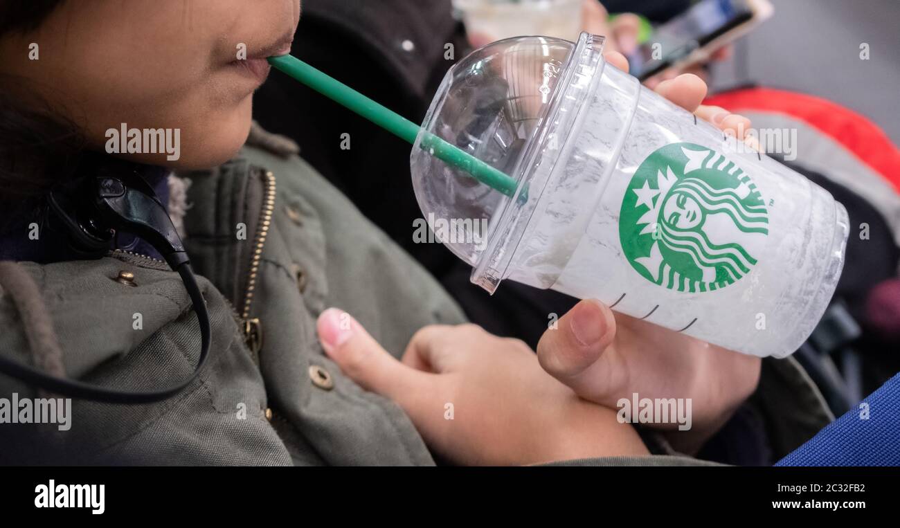 Ragazza che tiene e beve bevande Starbucks, Kyoto, Giappone in un treno pendolari. Foto Stock