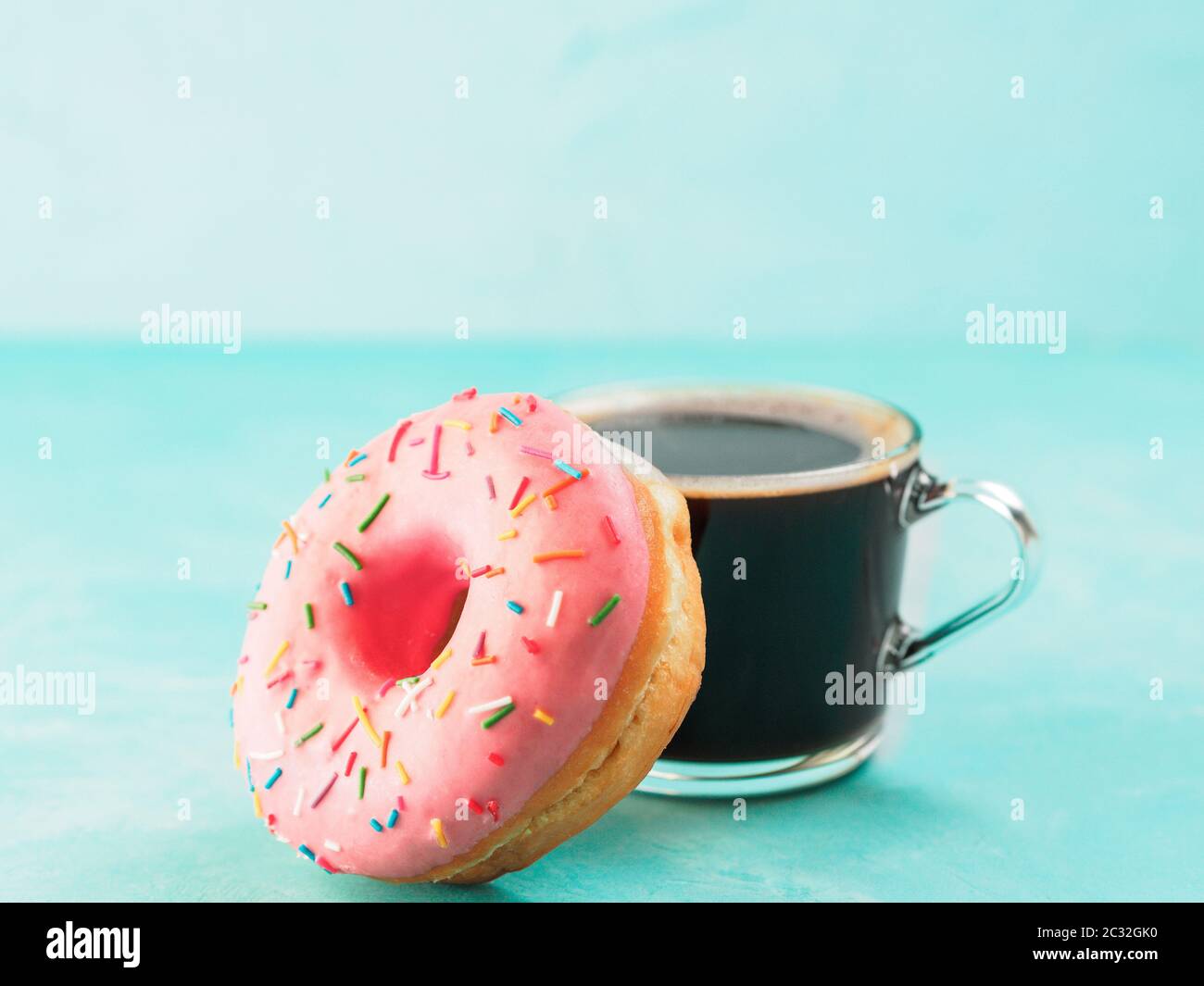 Rosa a ciambella e del caffè su sfondo blu , spazio di copia Foto Stock