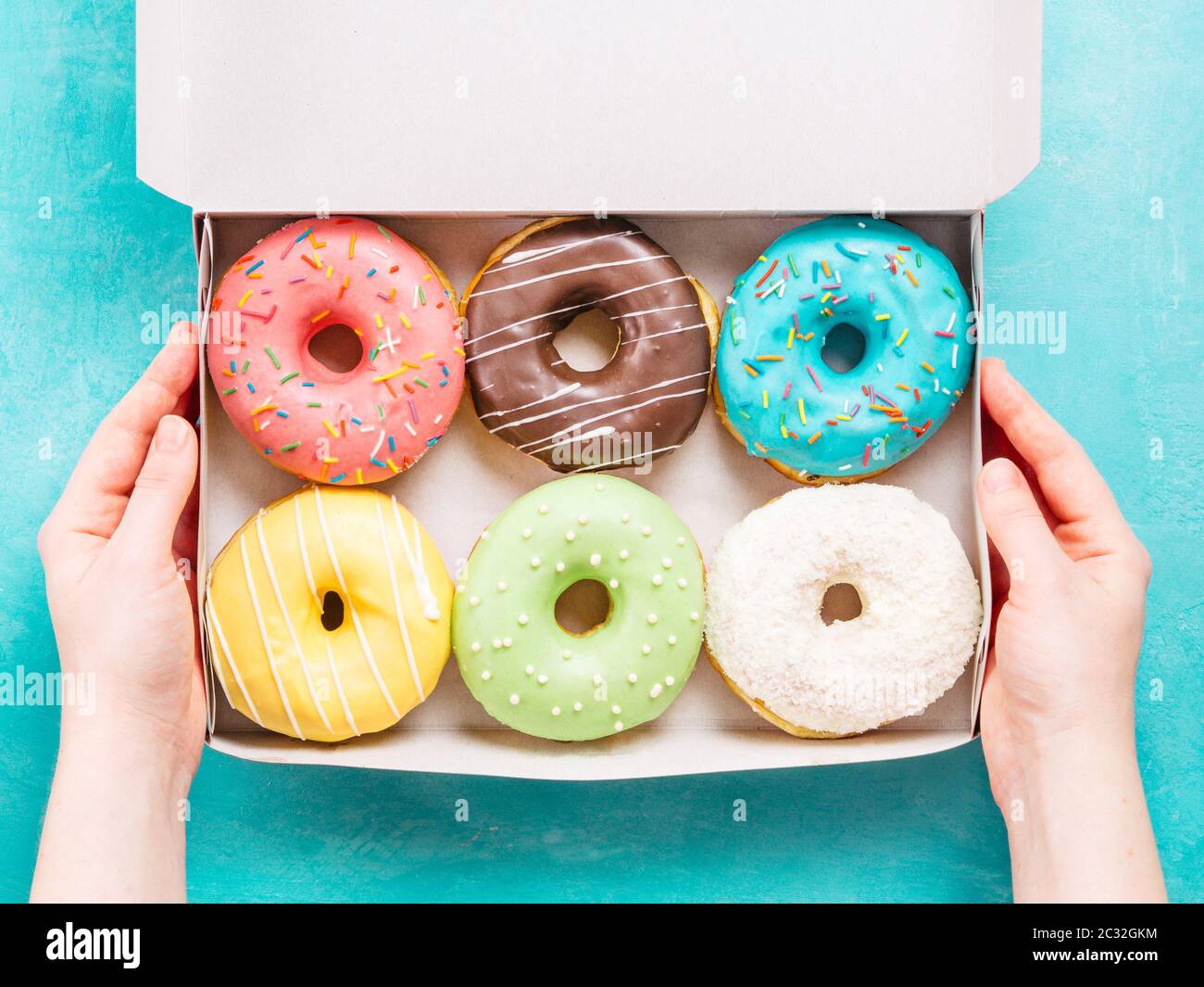 Le mani della scatola di contenimento con ciambelle Foto Stock
