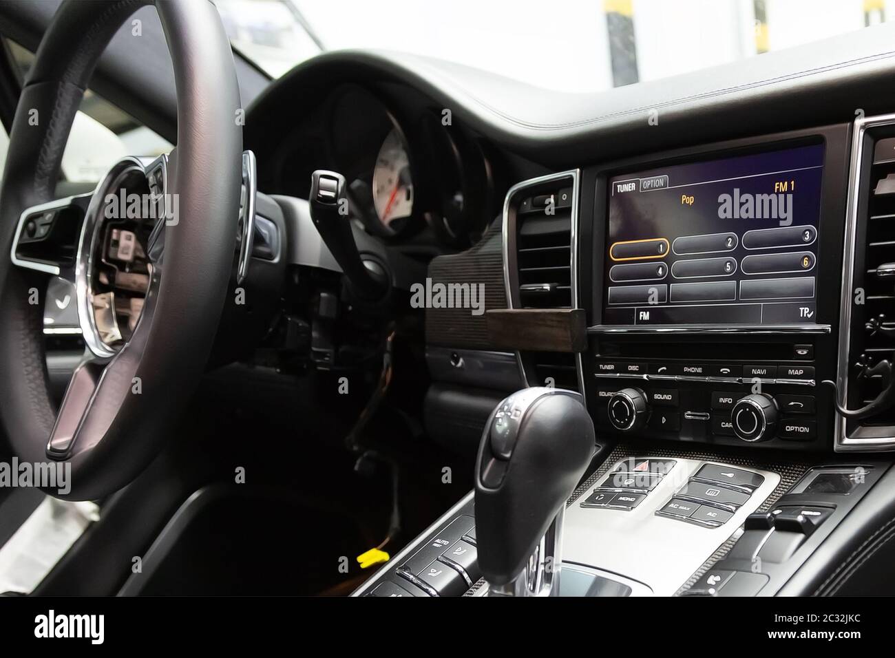 Rimosso dall'airbag del volante. Lavori di riparazione di auto sportive di lusso, esame in centro di assistenza. Interni auto smontati con pannelli in carbonio e bottoni Foto Stock