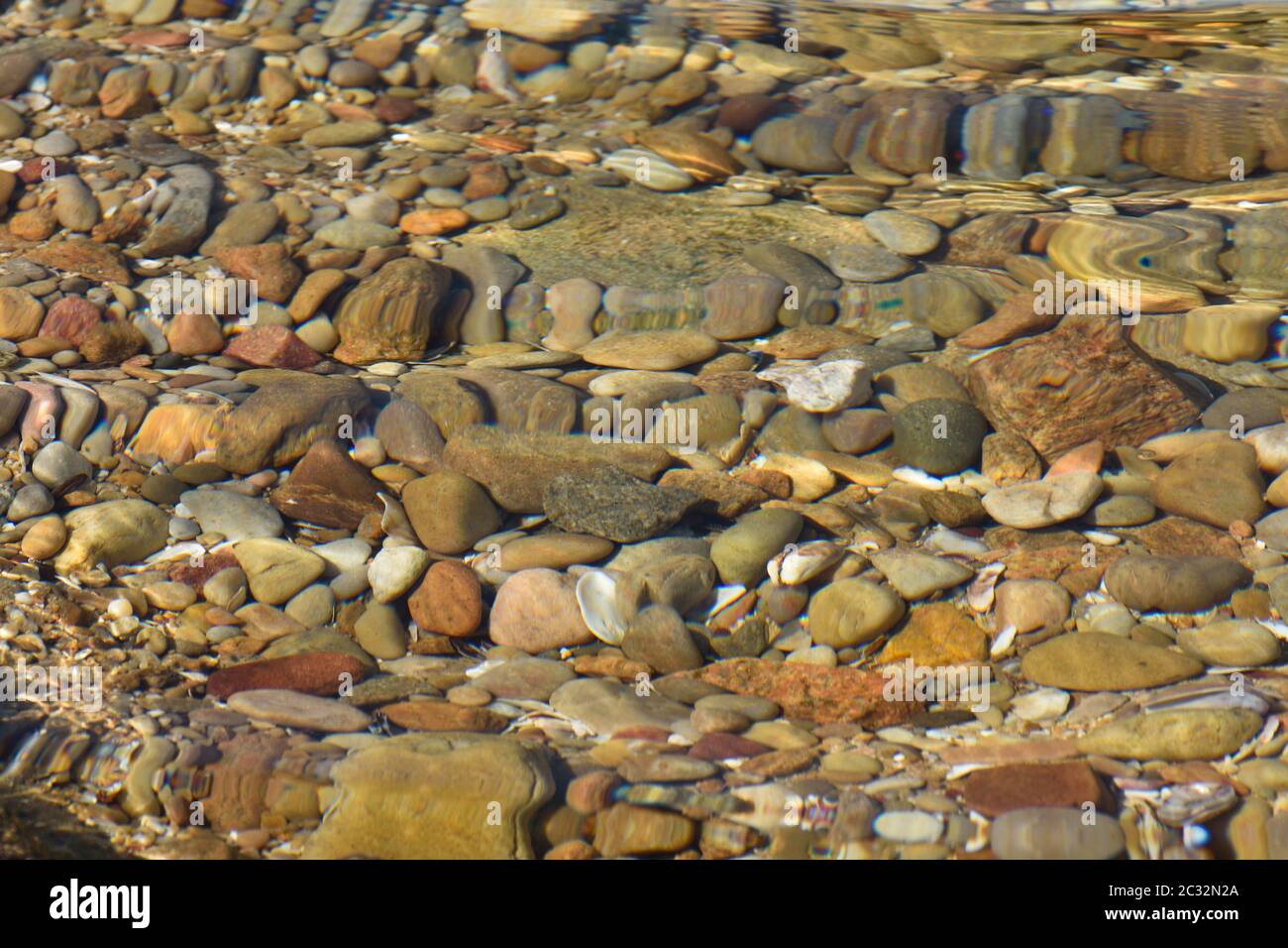 Acqua distorto rocce e Pebble in piscina costiera Foto Stock