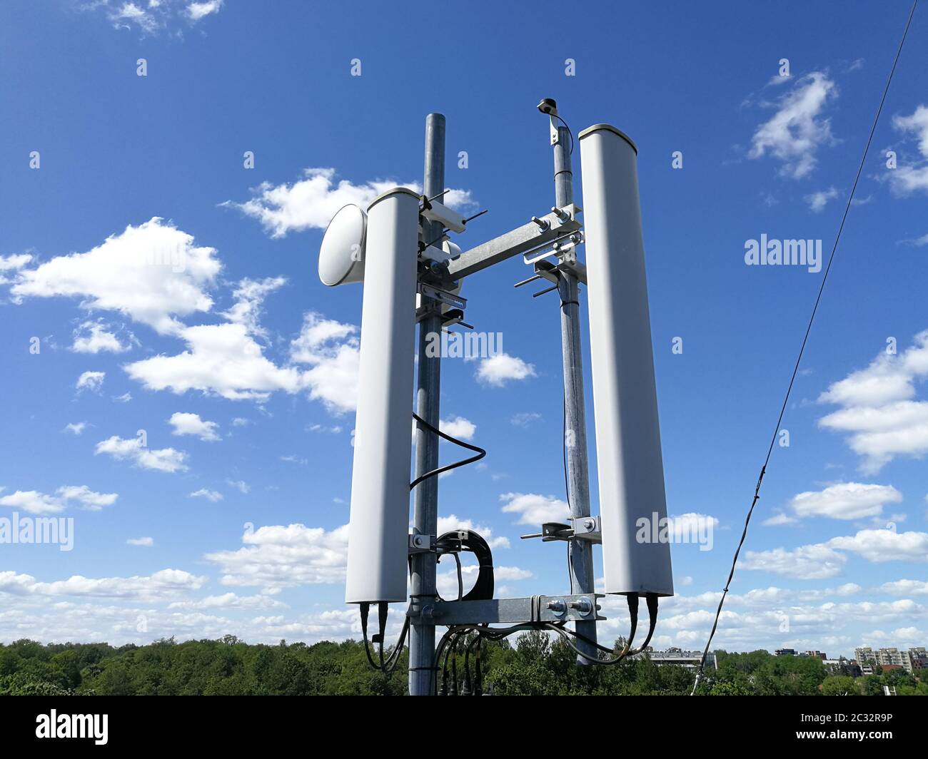 Stazione base GSM (Global System for Mobile Communication) e ripetitore di fronte al cielo blu nuvoloso per le telecomunicazioni Foto Stock