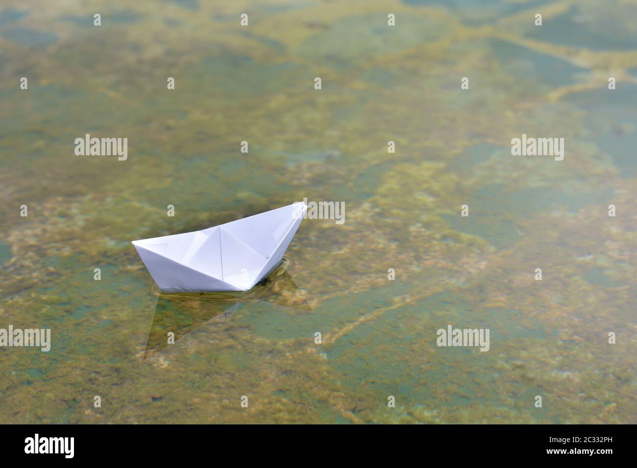 Barco de papel flotando sobre el agua de un estanque Foto Stock