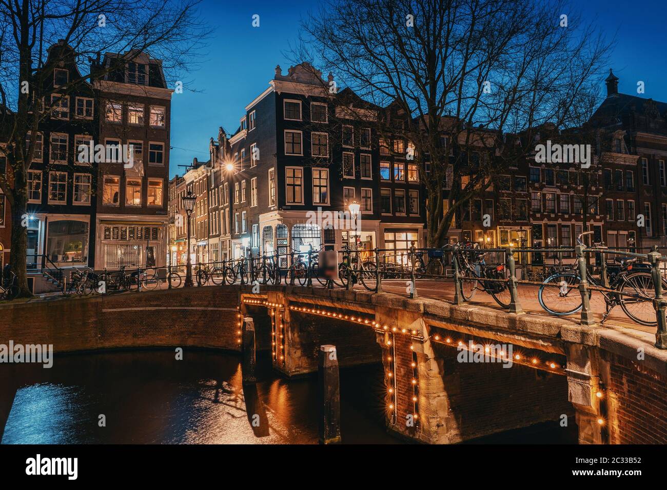 Amsterdam di notte, ponte sul canale d'acqua con luci serali e vecchie case, Amsterdam, Paesi Bassi. Foto Stock