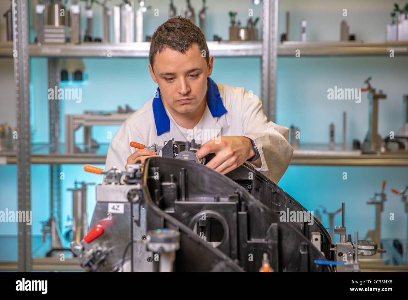 L'ingegnere misura componenti in plastica per la produzione di luci per l'industria automobilistica in uno stabilimento su una macchina digitale 3D. Foto Stock