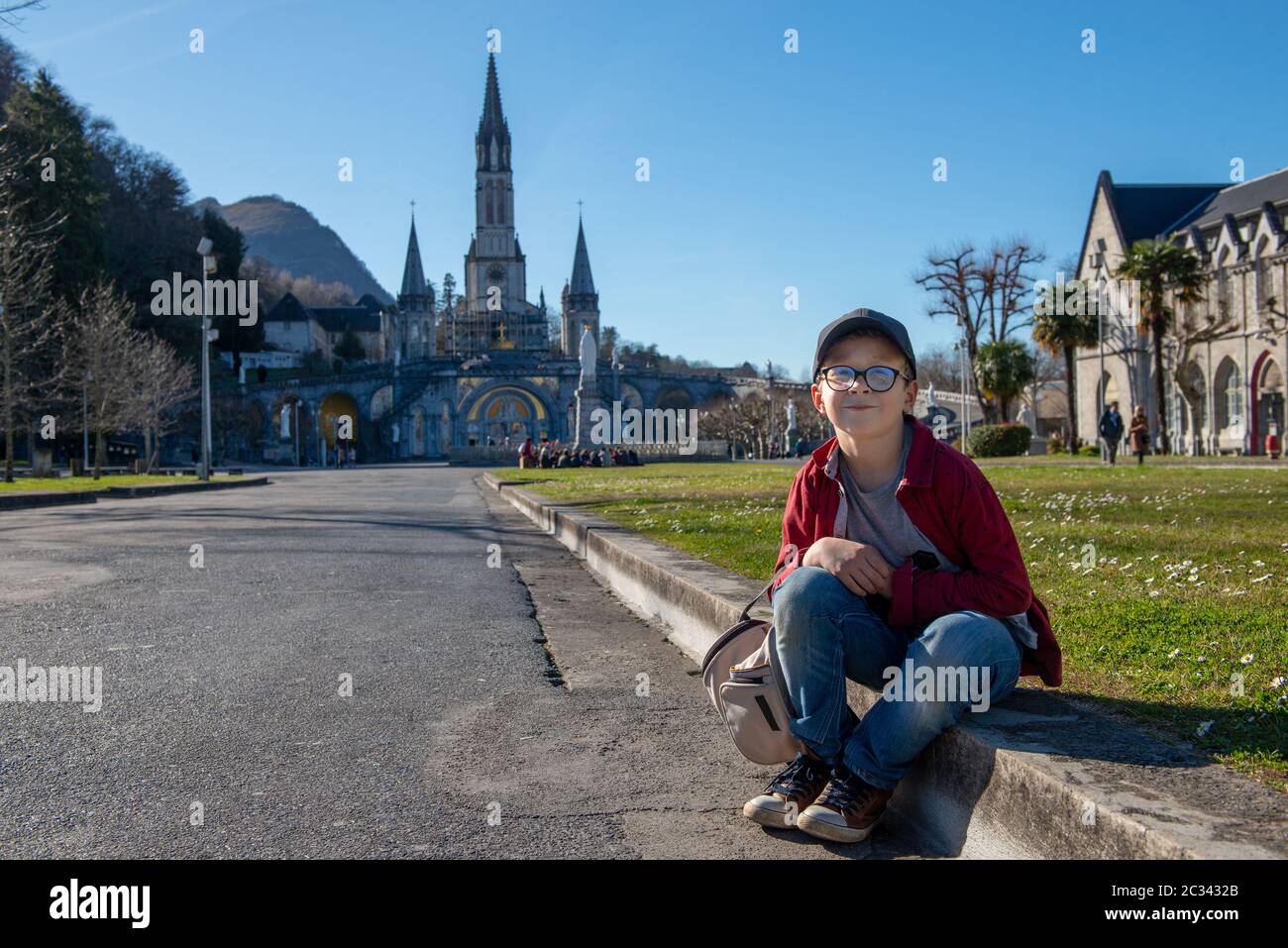 Un giovane ragazzo con la basilica di Lourdes in Francia Foto Stock