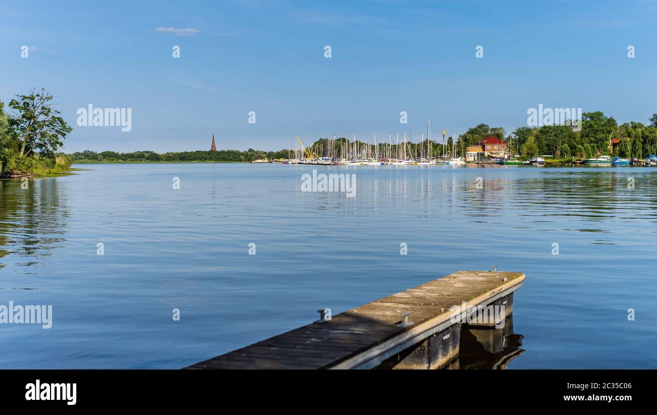 Barche a motore e a vela ancorate al molo laguna del lago o molo con canne e mete del fiume verde, bella giornata estiva sul porto turistico di Szczecin yacht, Polonia Foto Stock