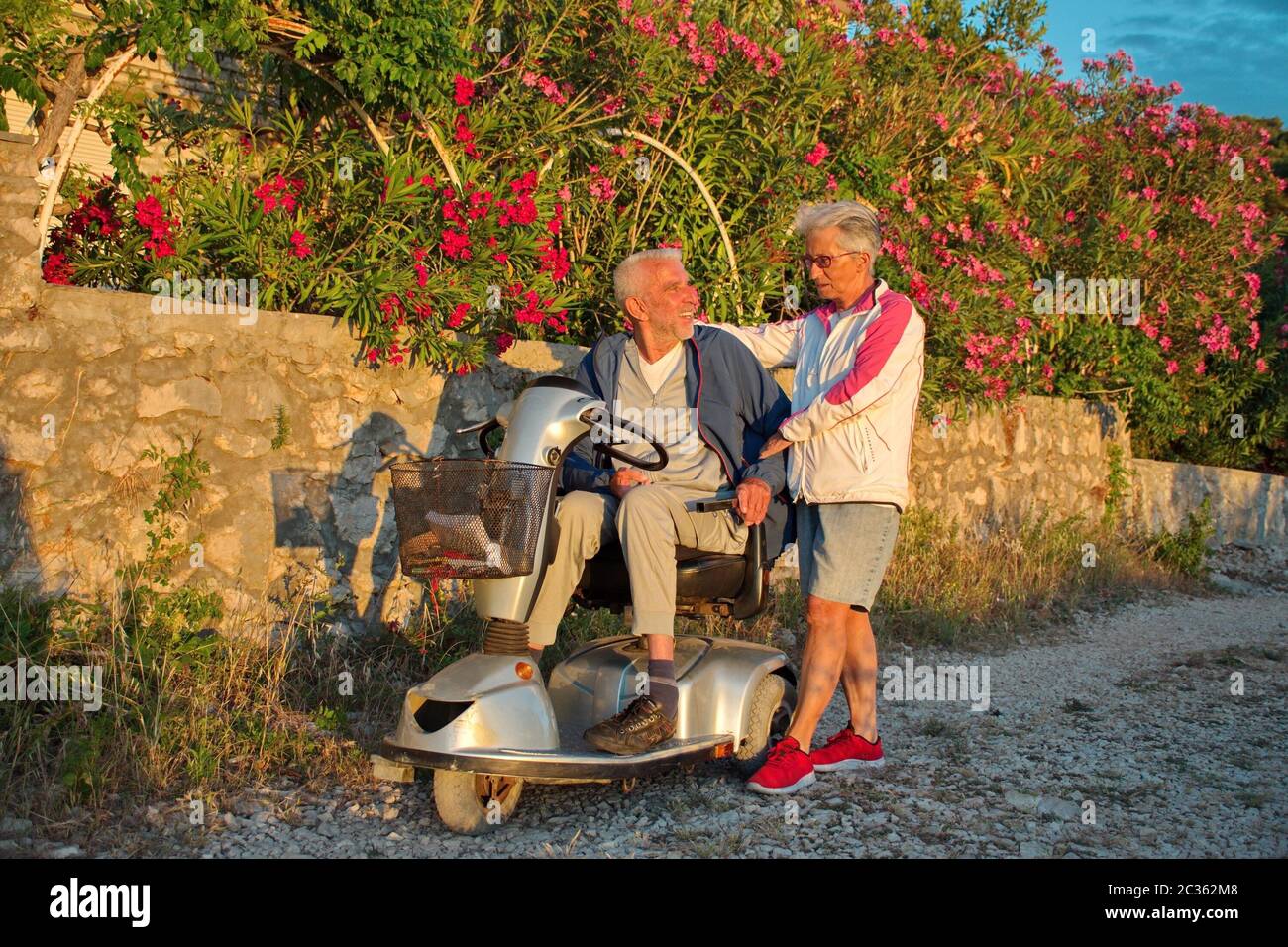 Coppia anziana che cammina lungo il lungomare Adriatico - uomo disabile in sedia a rotelle Foto Stock