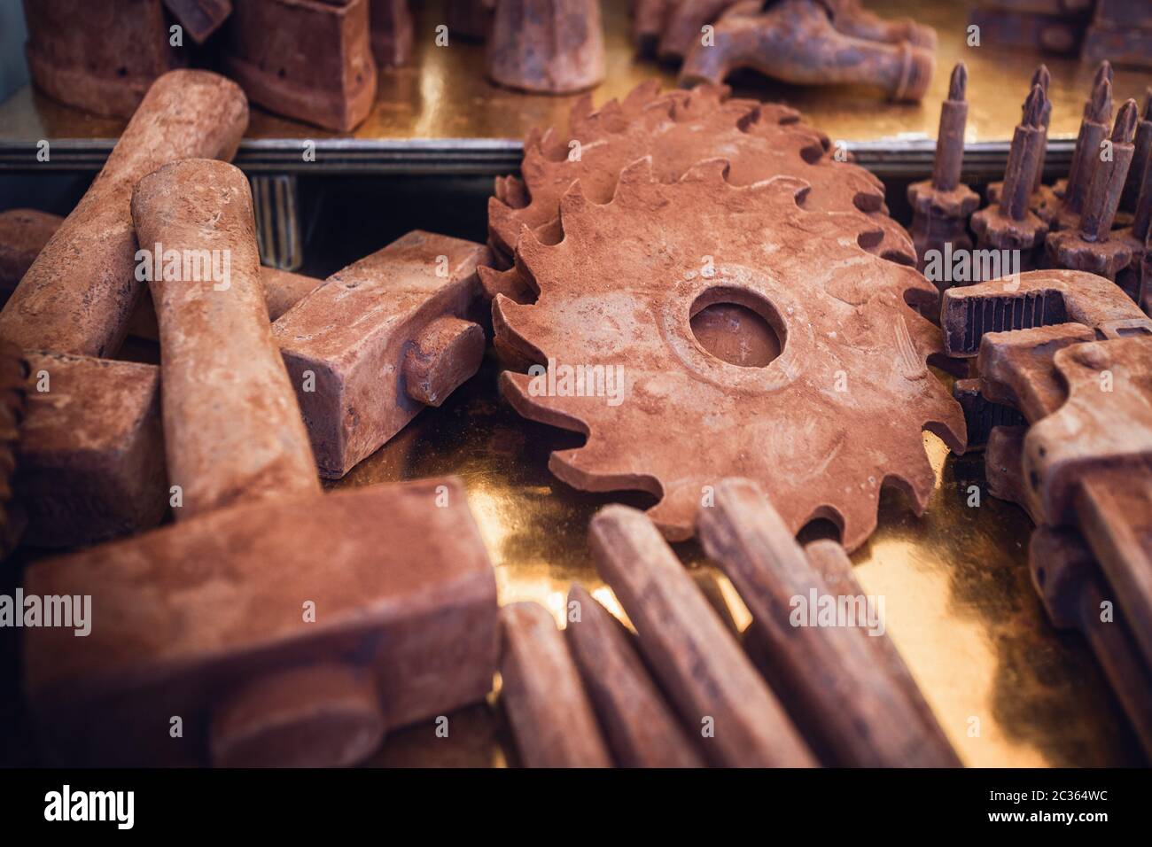 Utensili falsi come martello, cacciavite e lama circolare per sega realizzata con cioccolato sullo stand di mercato di un evento italiano di cioccolato in Piemonte Foto Stock