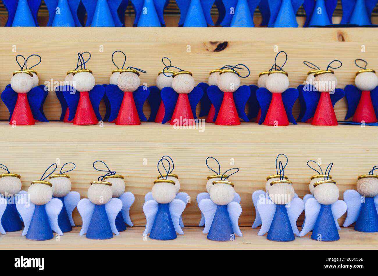 molti angeli in legno fatti a mano su una bancarella mercatino di natale, dipinto in rosso e blu Foto Stock