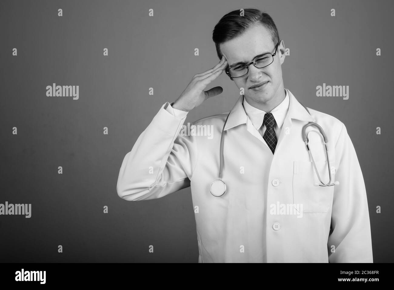 Giovane uomo bello medico contro uno sfondo grigio Foto Stock