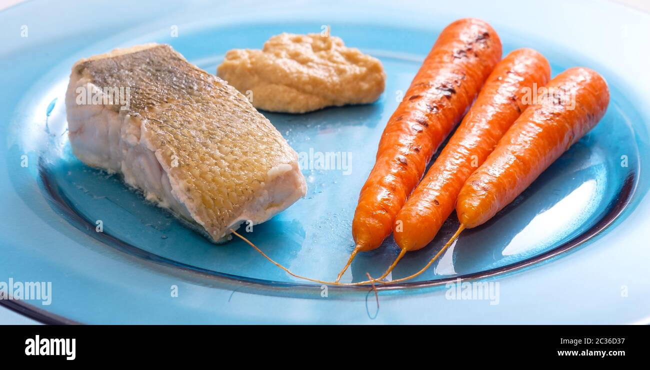 Zander di filetto di pesce arrosto con carote e hummus sulla piastra blu Foto Stock