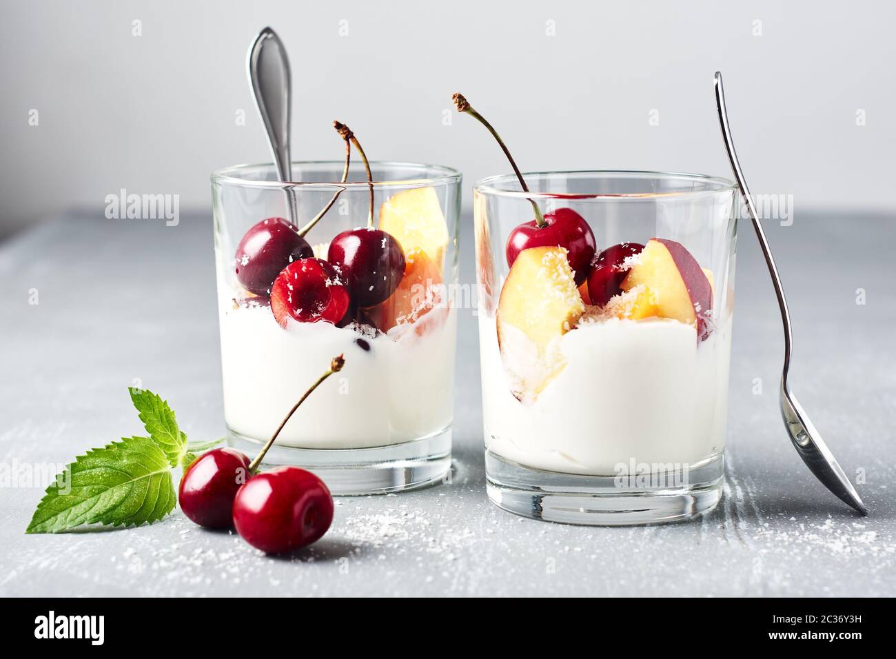 Yogurt greco con ciliegie e albicocche. Dessert estivo di frutta in un bicchiere. Foto Stock