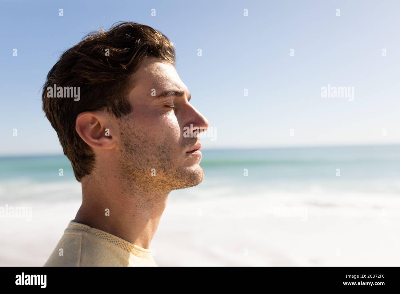 Giovane uomo caucasico che chiude gli occhi sulla spiaggia Foto Stock
