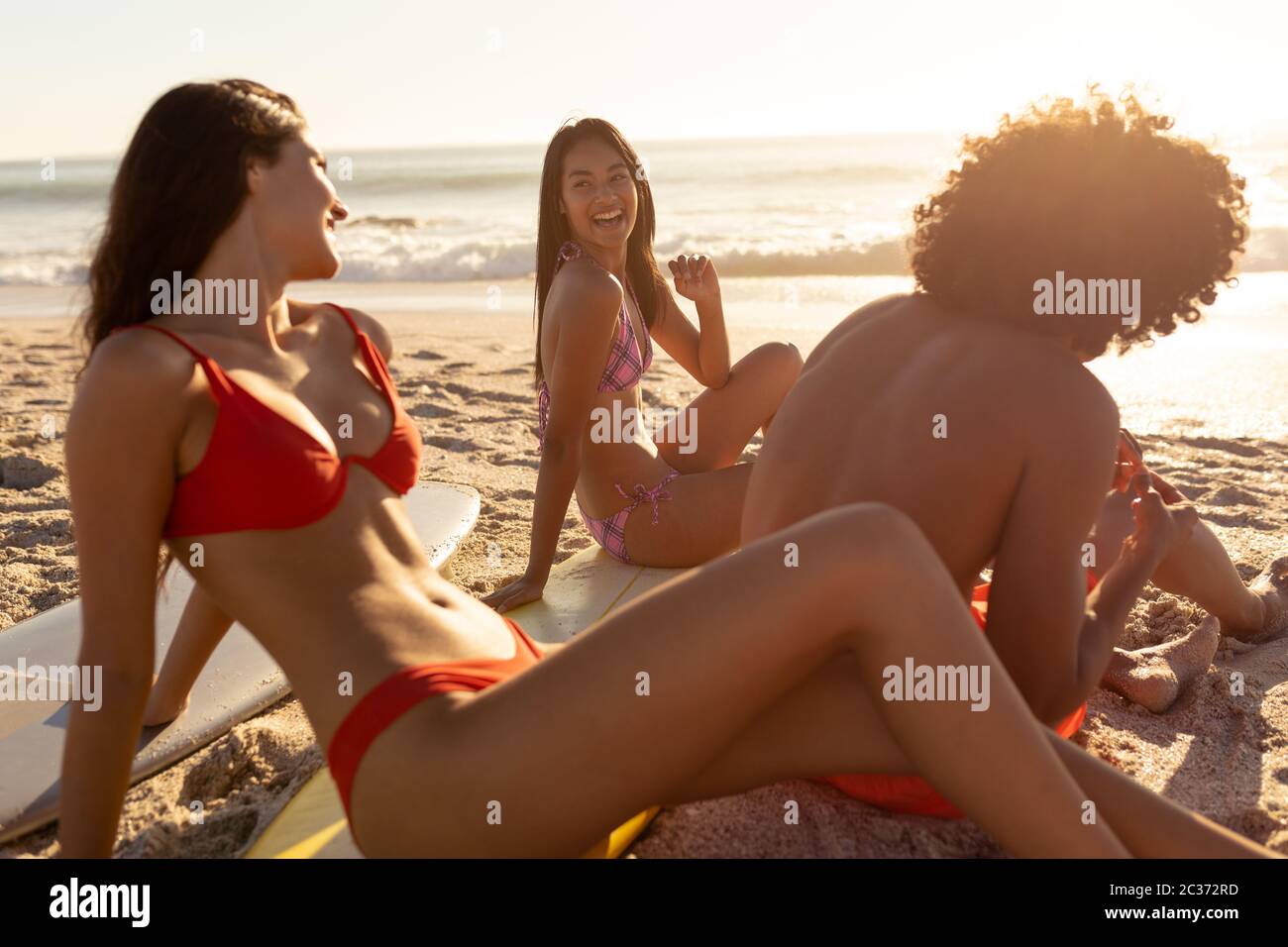 Giovani donne di razza mista sorridenti sulla spiaggia Foto Stock