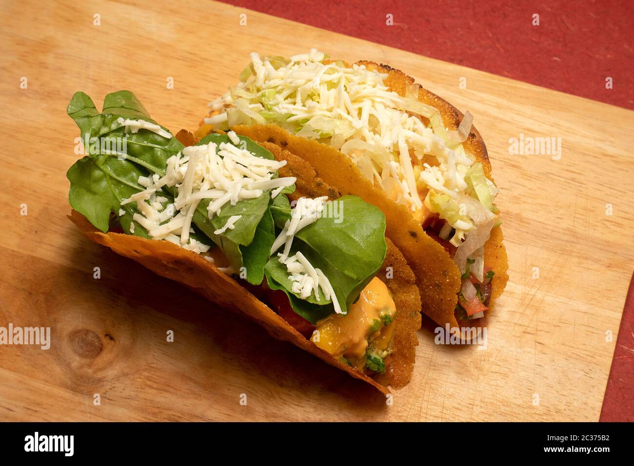TACOS MESSICANI CON FAGIOLI FRITTI, SALSA DI MANGO, SALSA DI POMODORO, SALSA DI CHIPOTLE, CONDITI CON LATTUGA, FORMAGGIO, FOGLIE DI ROQUETTE Foto Stock