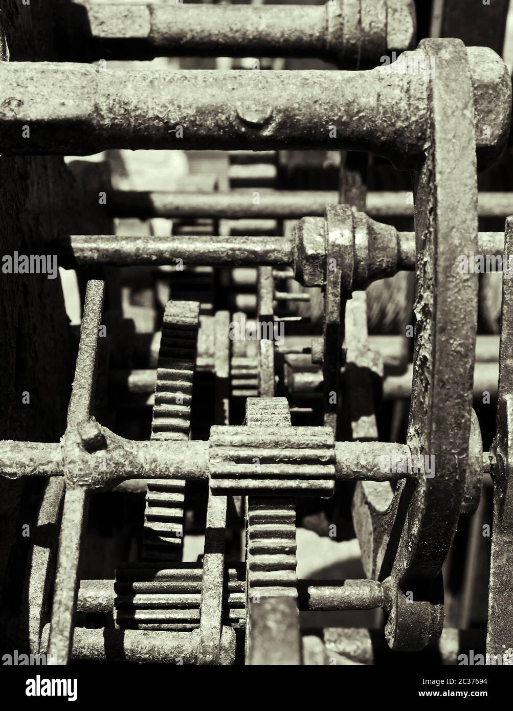 primo piano monocromatico di ingranaggi e ruote dentate complessi su vecchie macchine in acciaio arrugginito Foto Stock