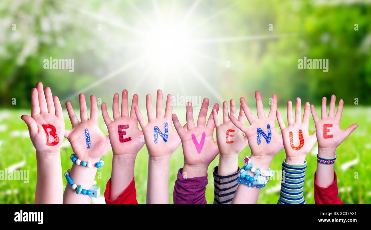 Bambini mani edificio colorato parola francese Bienvenue significa Benvenuti. Erba verde prato come sfondo Foto Stock