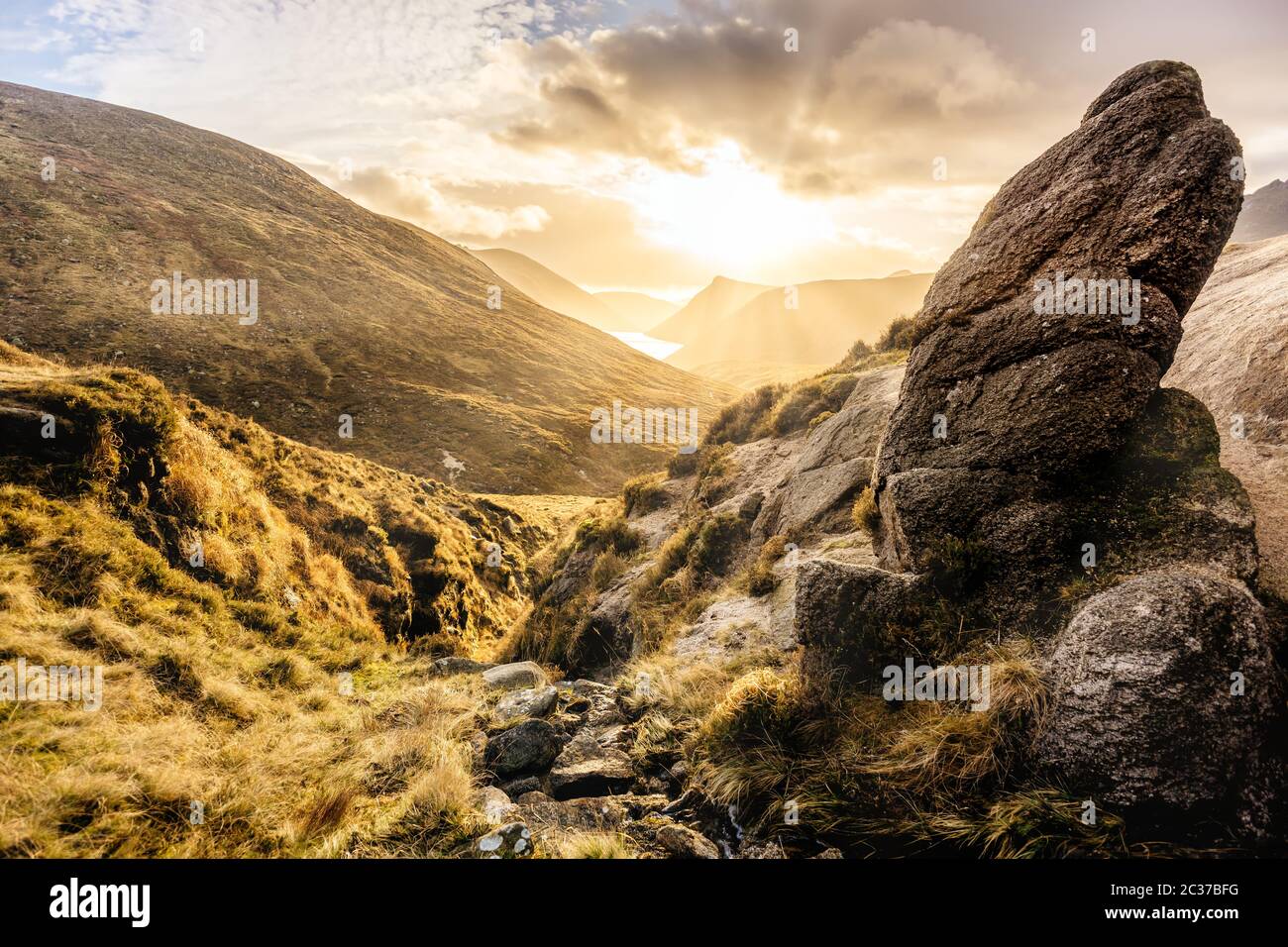 Grande masso e valle con serbatoio d'acqua, tramonto spettacolare con raggi solari. Montagne di Mourne Foto Stock