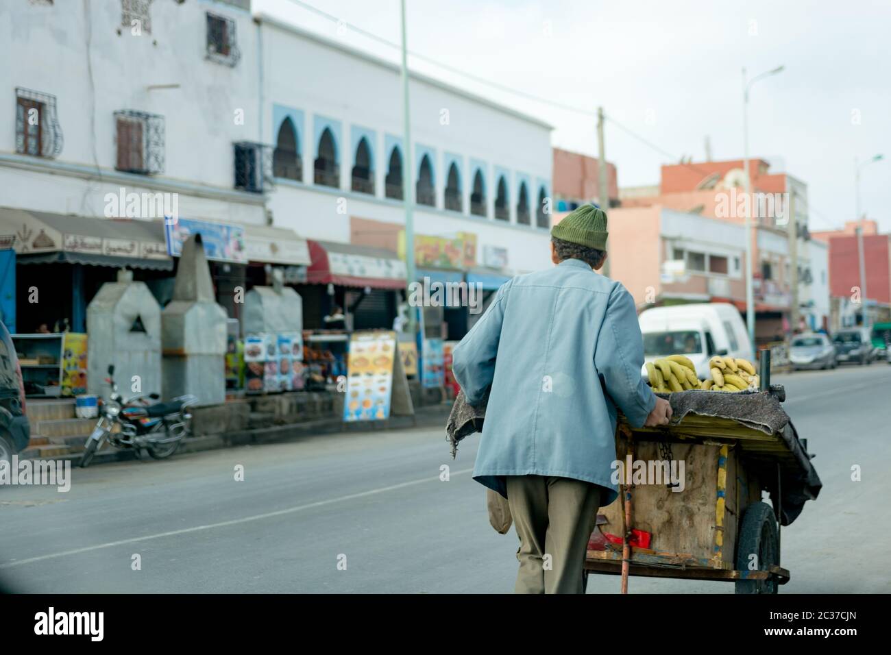 Essaouira, Marocco, 2019 febbraio: Vecchio uomo musulmano che vende limoni e frutta dal carrello al mercato di strada tradizionale in Marocco. Medina della città vecchia marocchina Foto Stock