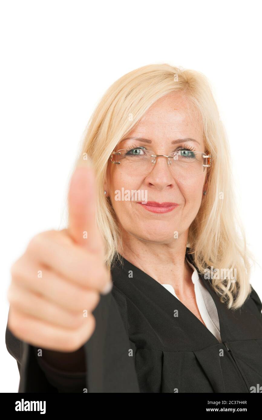 Vista frontale della testa e delle spalle di una donna bionda di mezza età in un accappatoio del giudice che mostra i pollici verso l'alto e sorridendo alla telecamera contro il dorso bianco Foto Stock