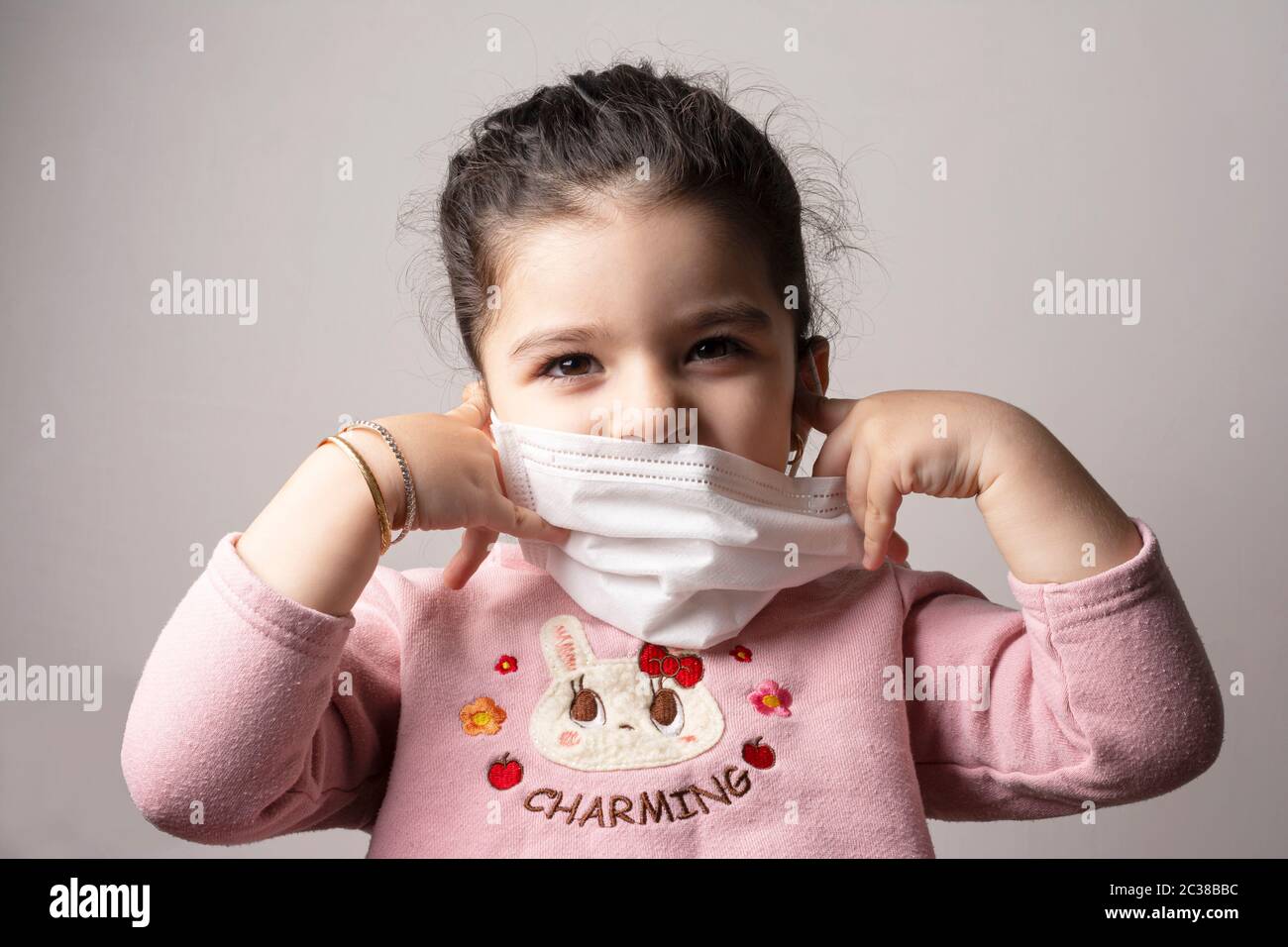 Bambina che rimuove la maschera dell'ospedale dal suo viso, scoppio di coronavirus e concetto di inquinamento atmosferico Foto Stock