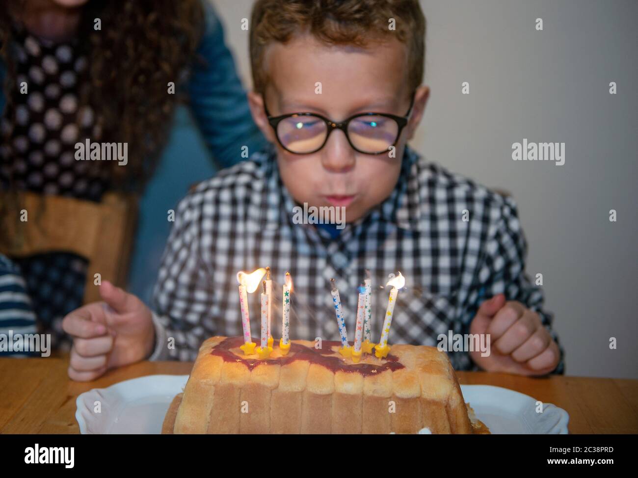 Un ragazzino soffiando candele sulla torta, felice festa di compleanno Foto Stock