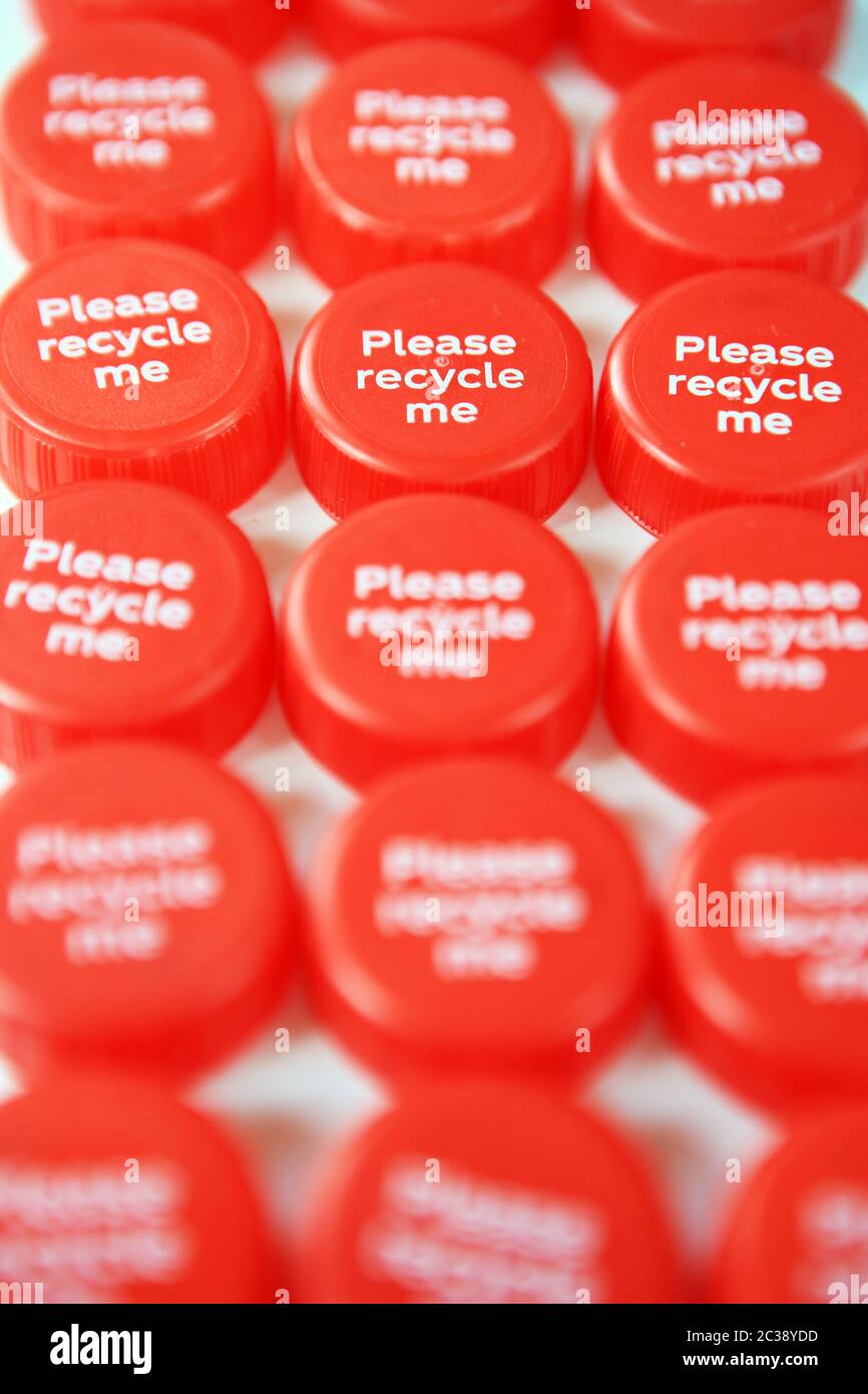 Coperchi in plastica per bottiglie con alcuni che dicono "Please recycle me" (Ricicla prego) Foto Stock