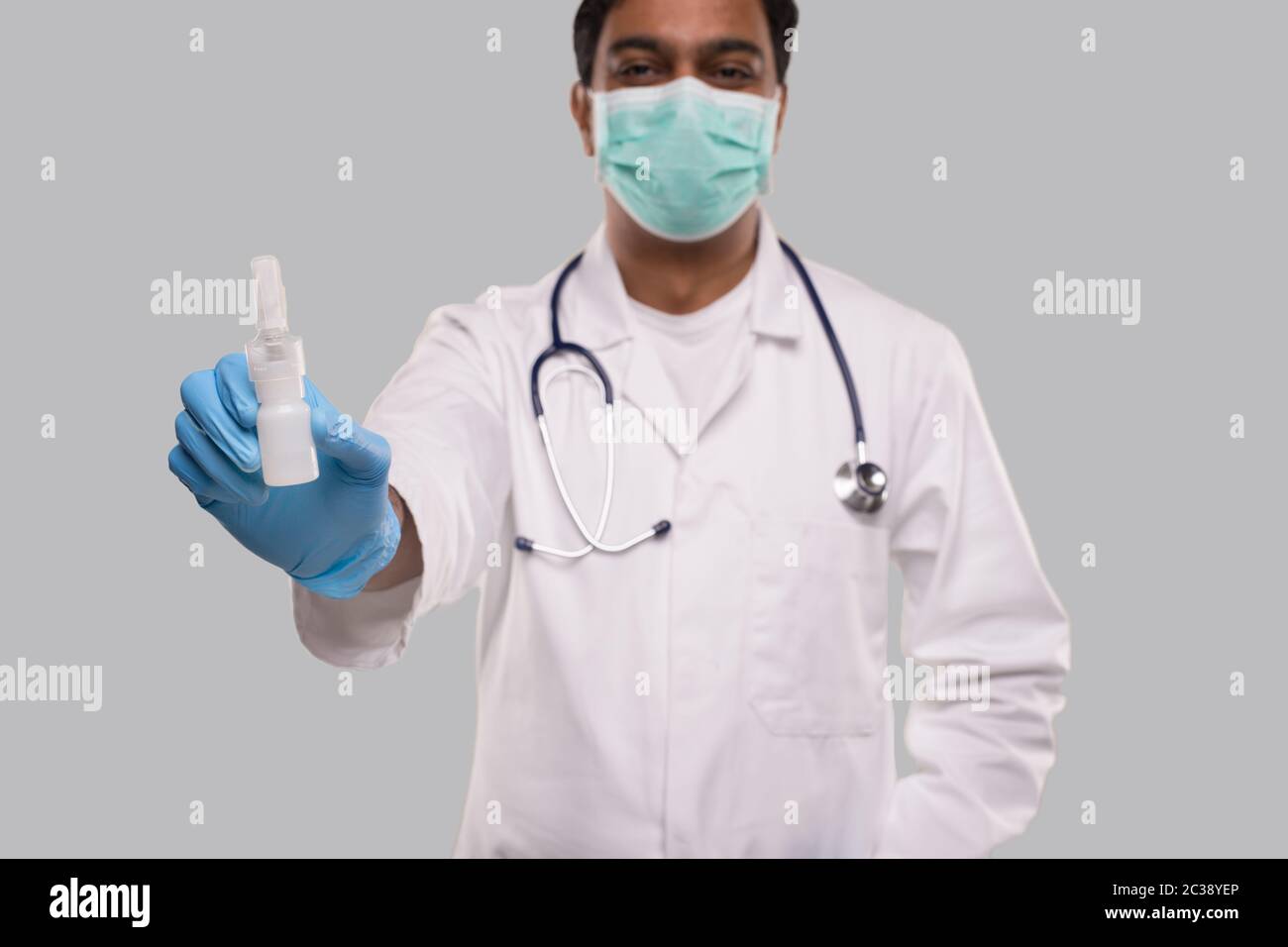 Medico che mostra spray al naso indossare maschera medica e guanti primo piano. L'uomo indiano medico spray nasale. Concetto di virus corona. Isolato Foto Stock
