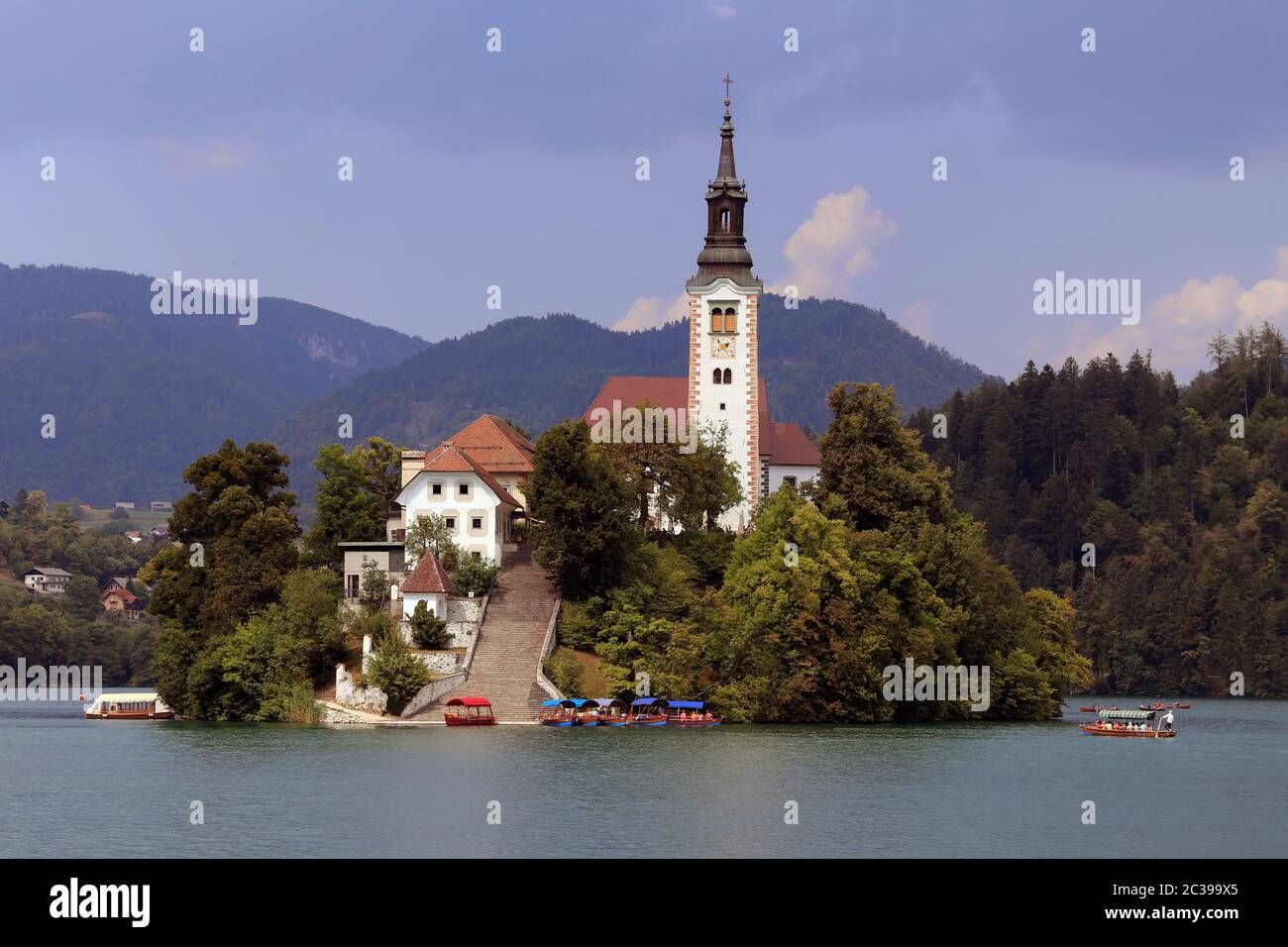 Chiesa di Santa Maria sull'isola nel lago Bled con Pletnas come barche tradizionali a remi Foto Stock