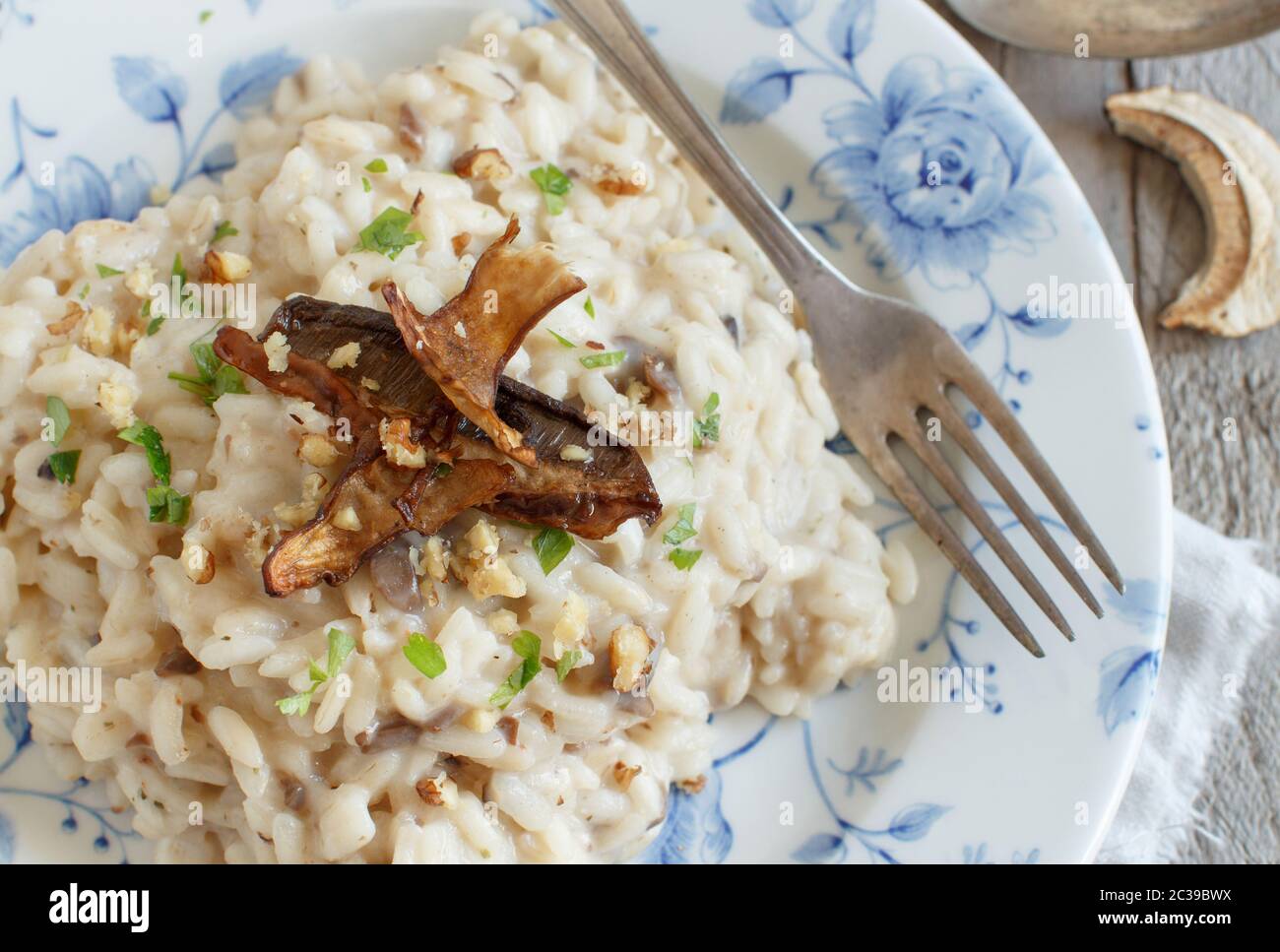 Risotto con funghi porcini su una piastra blu su una tavola di legno Foto Stock