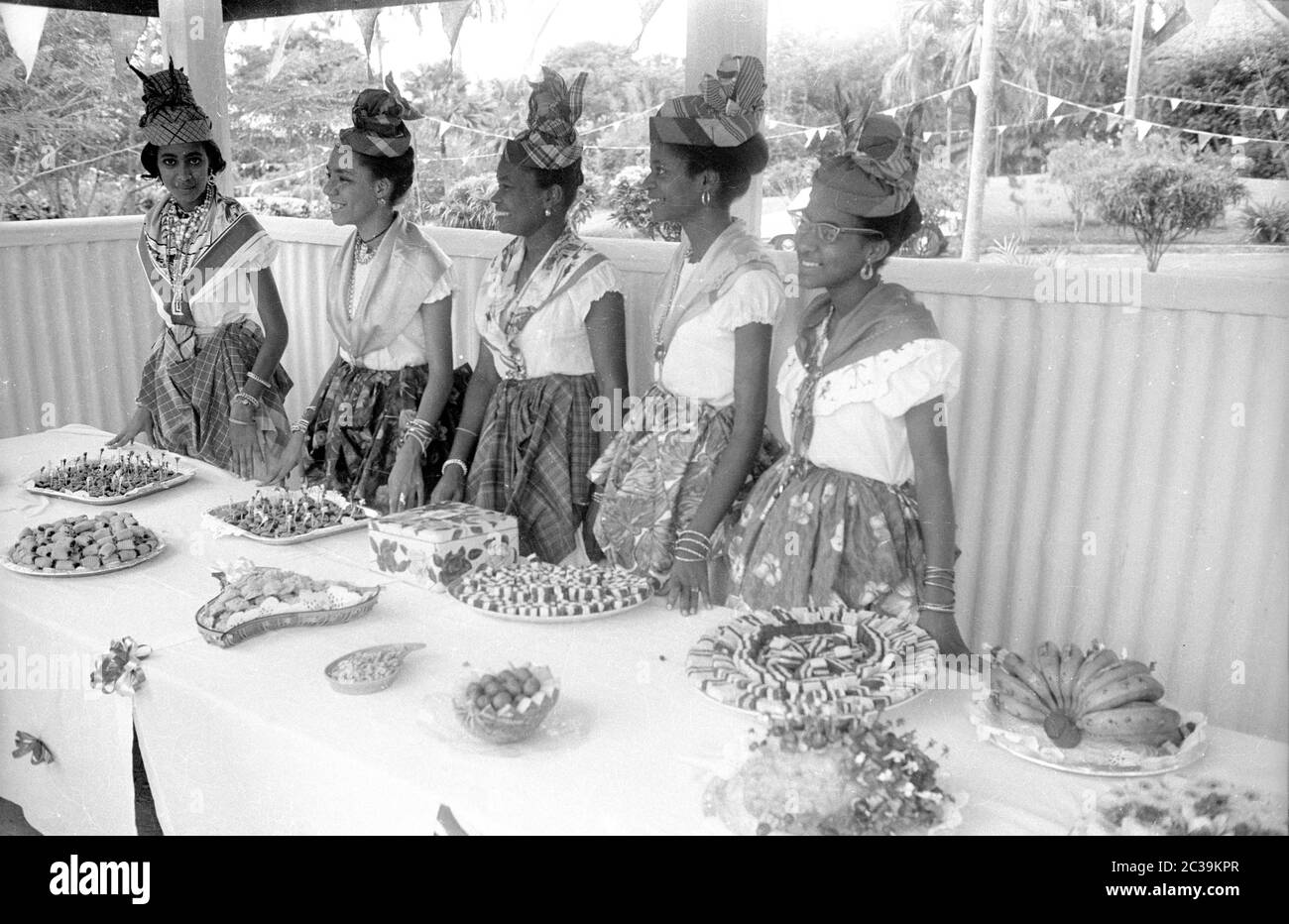 Durante la visita della regina britannica Elisabetta II alla colonia britannica di Antigua, è accolta per cerimonie davanti ad un buffet da donne locali vestite in costumi tradizionali. Foto Stock