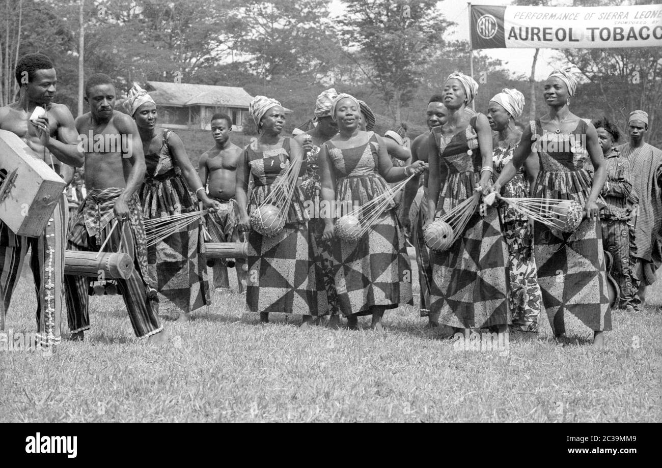 Uomini e donne della Sierra Leone fanno musica e ballano in costumi tradizionali. Foto Stock