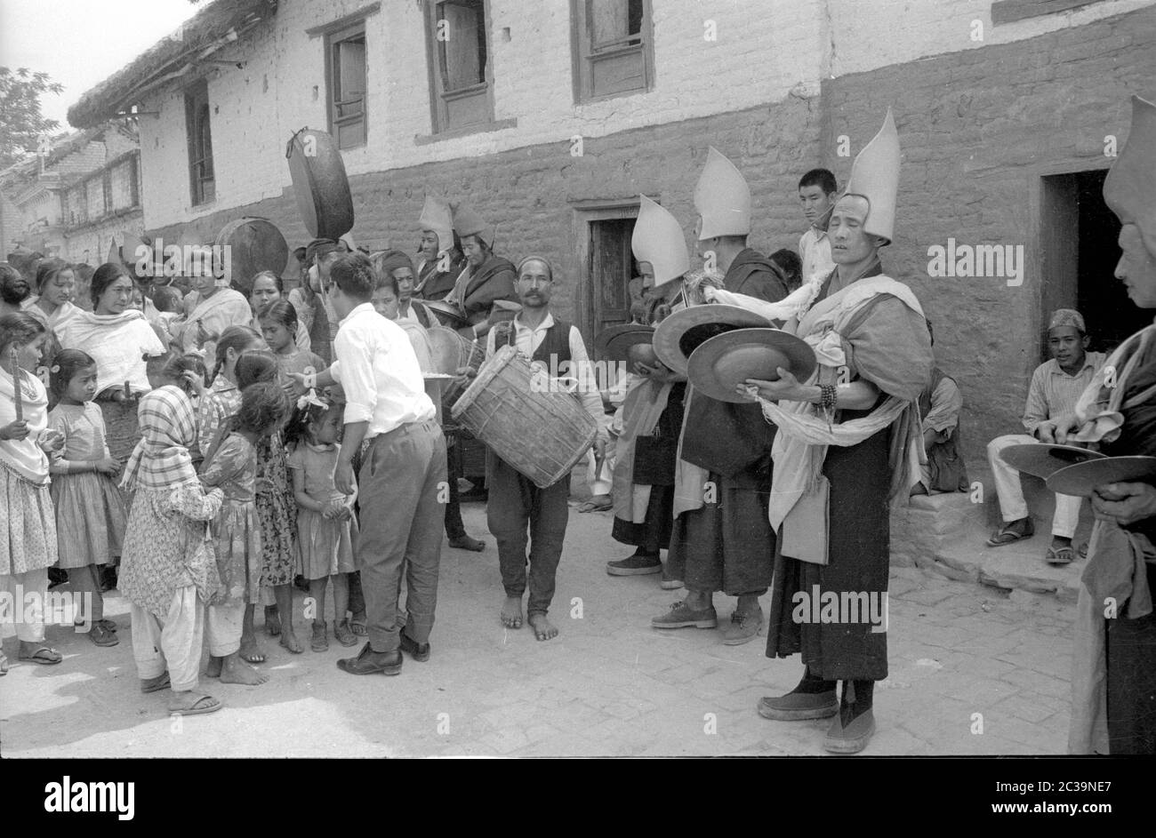 I monaci in Nepal fanno musica per un gruppo di bambini e le loro madri. Foto Stock