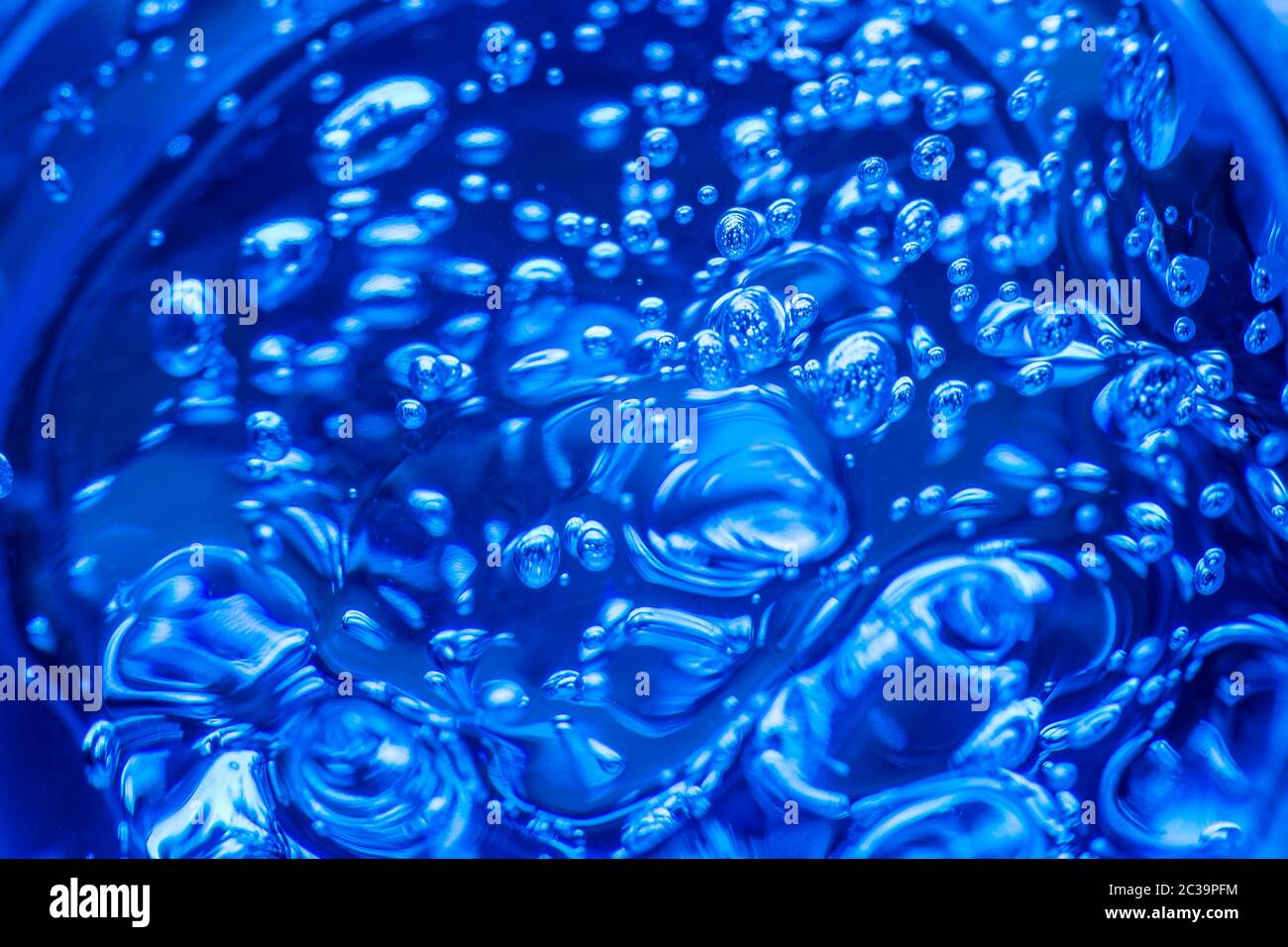 Gel liquido su uno schermo digitale di microscopio o acqua di scannonamento. Bolle di ossigeno in un bicchiere d'acqua su sfondo blu. Minera Foto Stock