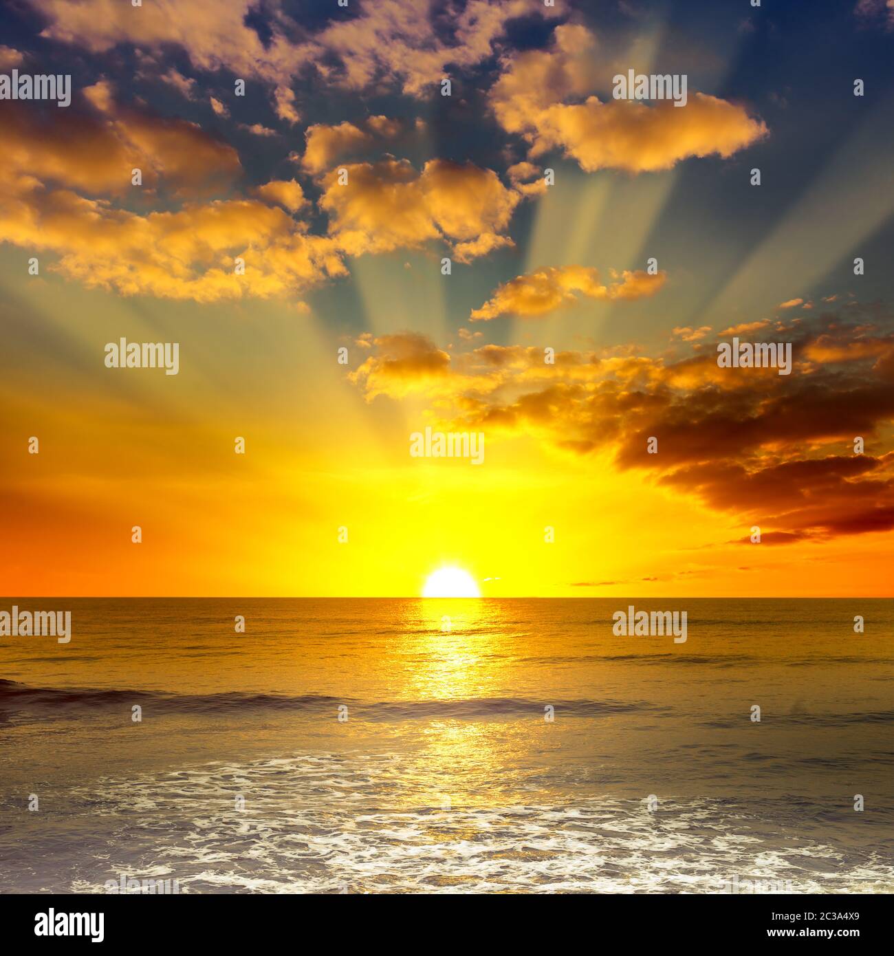 Maestosa e luminosa alba sull'oceano e nuvole arancioni sul cielo blu. Foto Stock