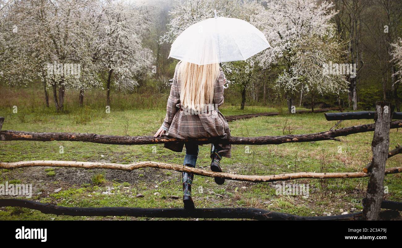 Solitaria donna godendo la natura in fioritura frutteto in pioggia tempo fresco Foto Stock