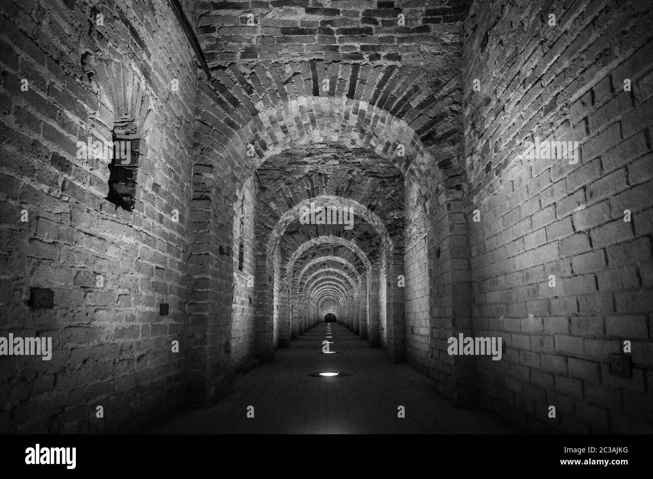 Arco a tunnel in mattoni rossi come passaggio tra le due ali di un castello medievale. Pietra di granito un mattone costruito in Foto Stock