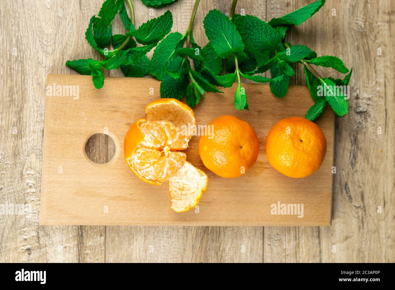 Tre tangerini su tavola di legno con menta Foto Stock