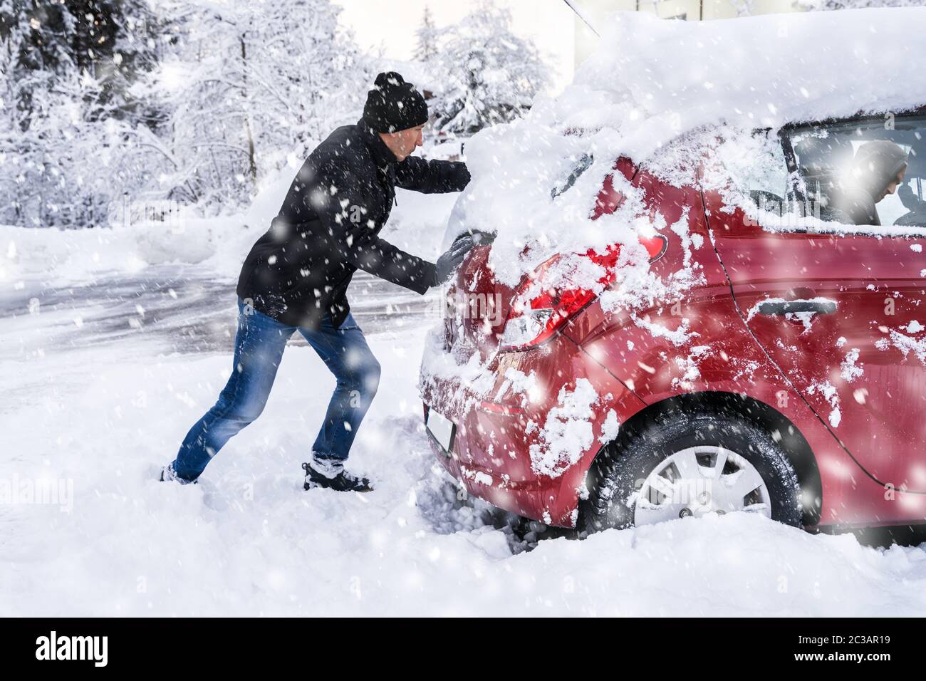 L'uomo spingendo una vettura bloccato nella neve dopo la nevicata Foto Stock