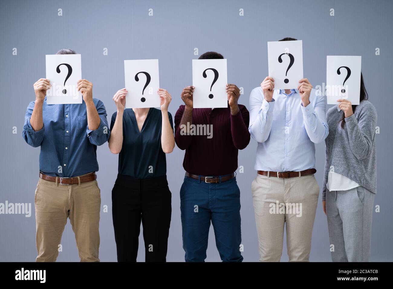 Gruppo di Business non identificabili persone che si nascondono sotto un punto interrogativo Foto Stock