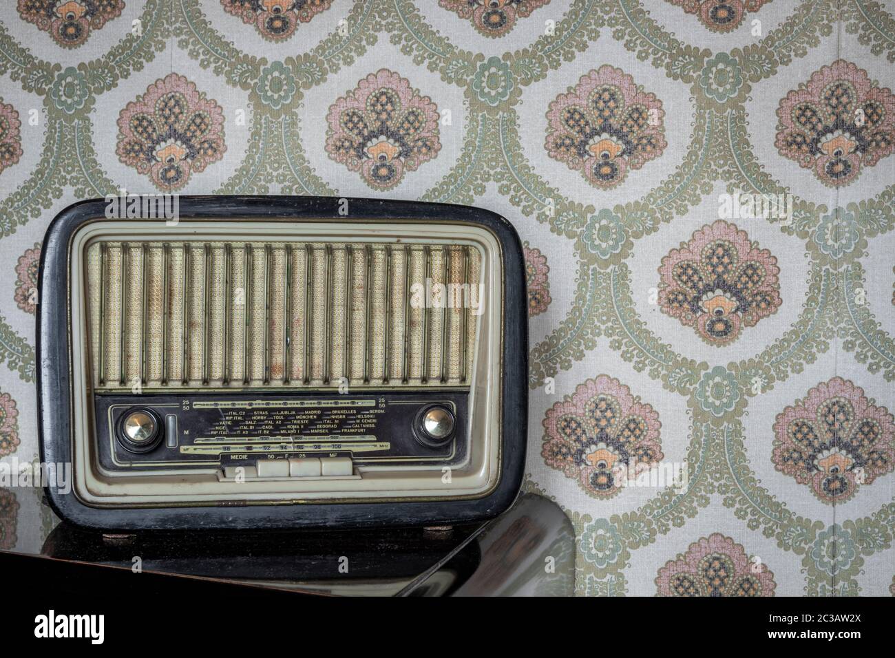 Una vecchia radio a transistor, con manopole e pulsanti per la  sintonizzazione manuale. Sullo sfondo una carta da parati vintage. Oggetto  antico, indossato e rovinato dal tempo Foto stock - Alamy
