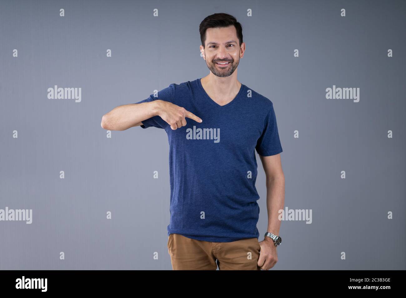 Uomo sorridente in Casuals puntamento permanente a T-Shirt Foto Stock