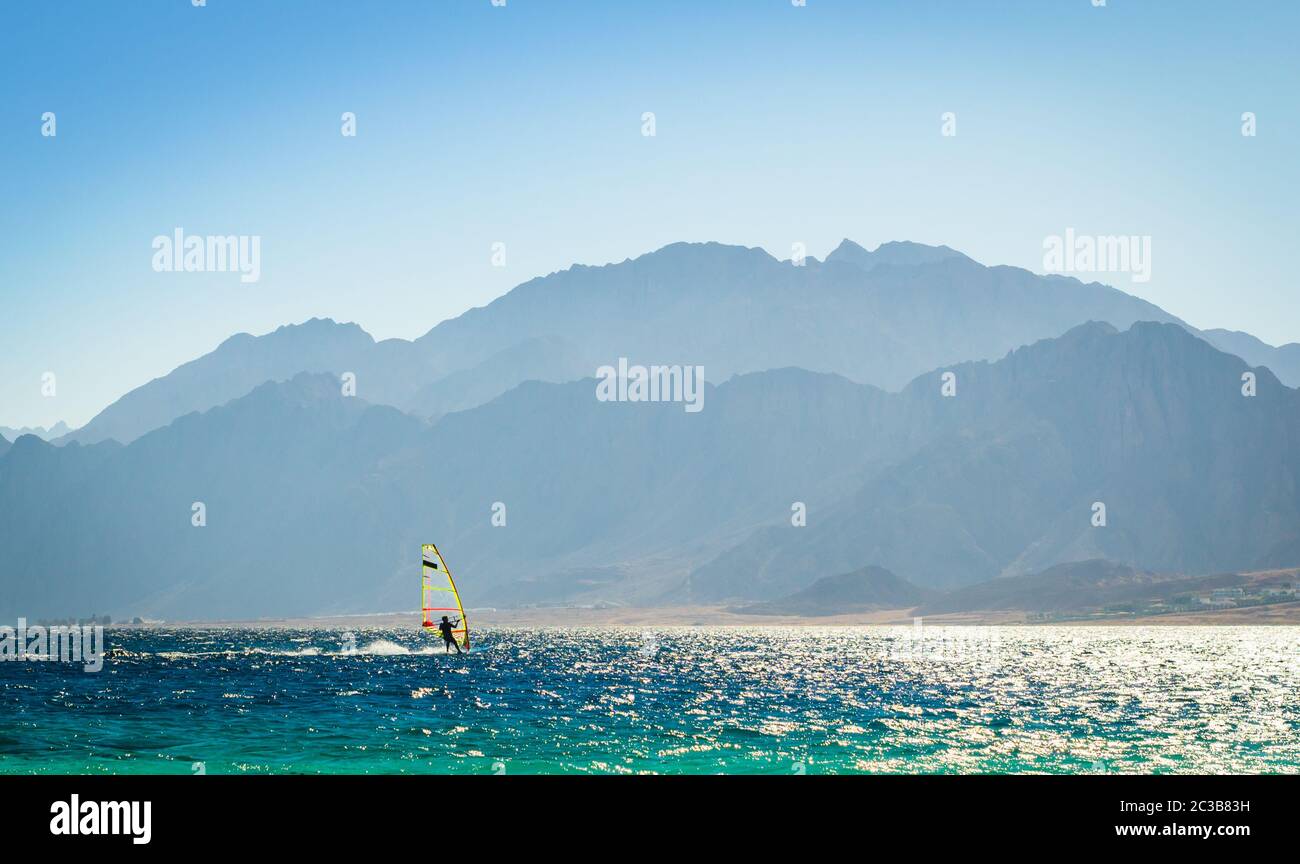 Surfer corse in mare contro lo sfondo delle alte montagne rocciose in Egitto Dahab Foto Stock