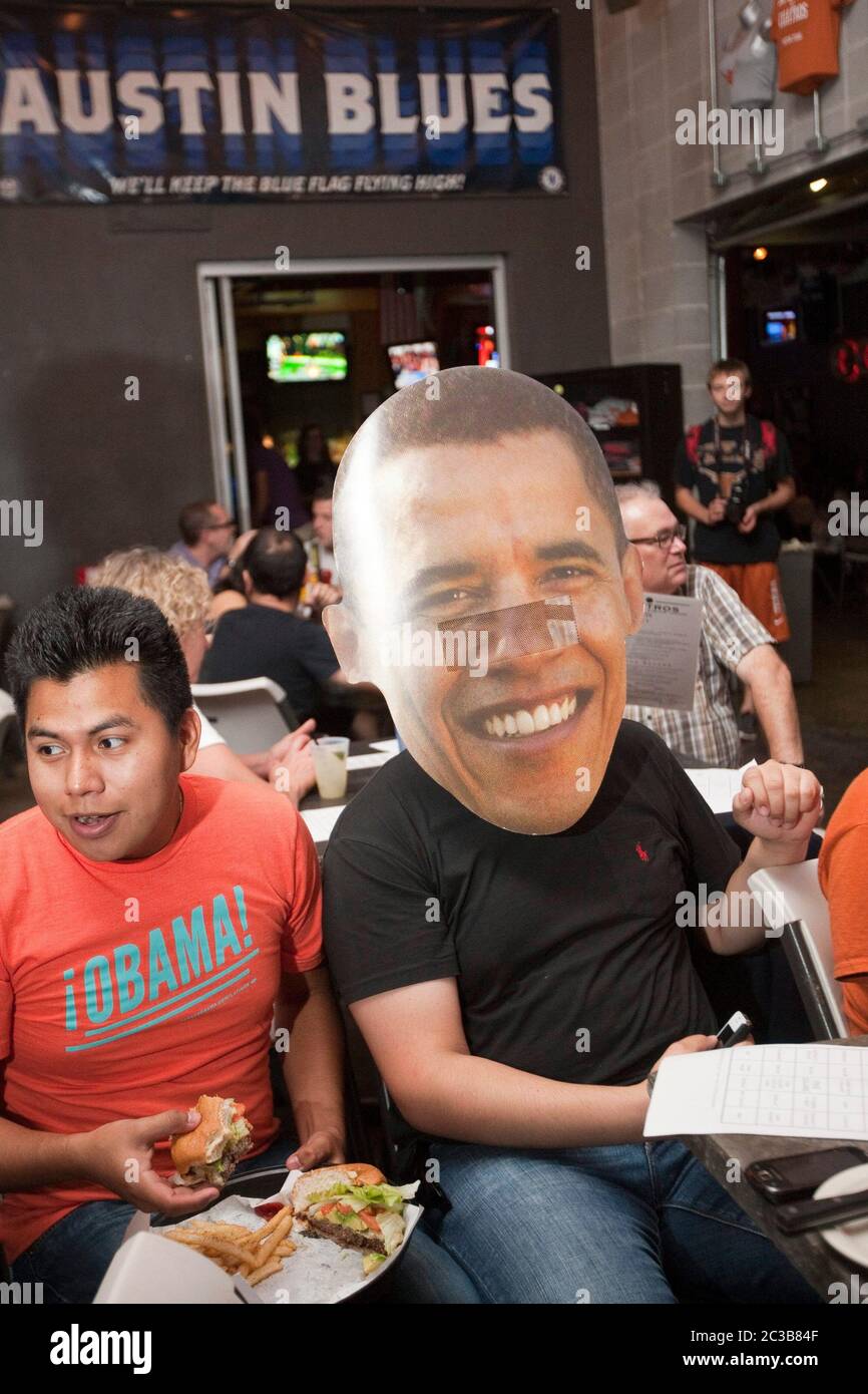 Austin, Texas USA, 3 ottobre 2012: Un grande gruppo partecipa a una festa di guardia per il primo dibattito presidenziale Mitt Romney/Barack Obama in TV da un ristorante vicino al campus dell'Università dei tè. Questo sostenitore di Obama sta portando un manifesto di 'fahead' del volto di Pres. Obama. ©MKC / Daemmrich Photos Foto Stock Austin, Texas USA, 3 ottobre 2012: Un grande gruppo partecipa a una festa di guardia per il primo dibattito presidenziale Mitt Romney/Barack Obama in TV da un ristorante vicino al campus dell'Università dei tè. Questo sostenitore di Obama sta portando un manifesto di 'fahead' del volto di Pres. Obama. ©MKC / Daemmrich Photos Foto Stock