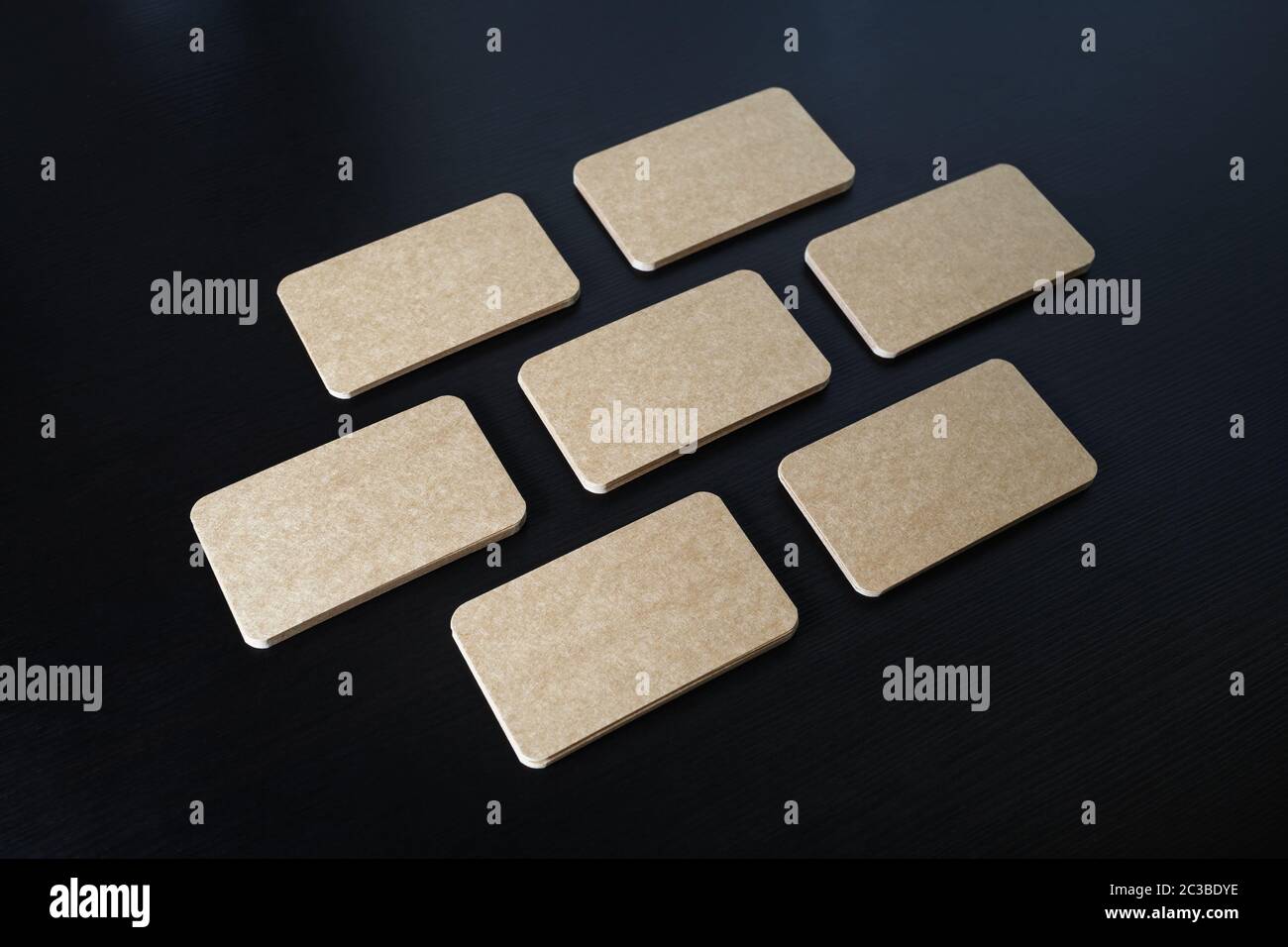 Foto di blank kraft carte aziendali su nero lo sfondo di legno. Modello per ID. Foto Stock