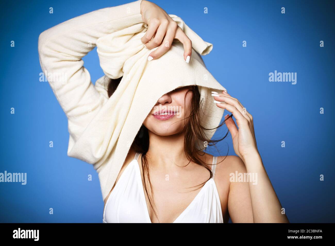 Felice giovane femmina sorridente e decollo morbido e caldo maglione su sfondo blu Foto Stock