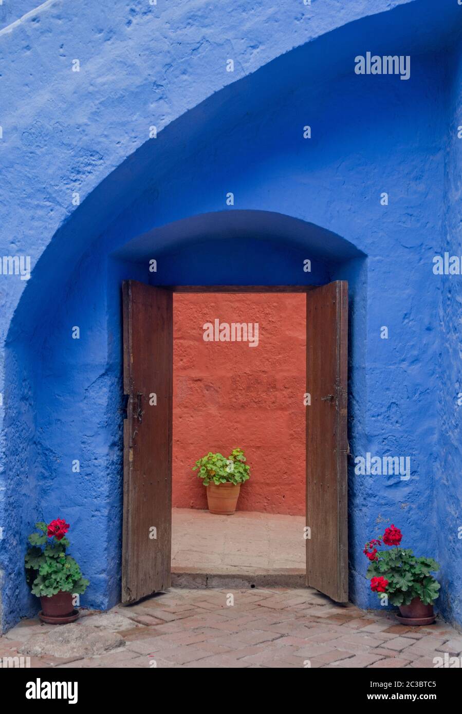 Angolo pittoresco e colorato con vasi di fiori, antica porta aperta e bella parete blu nel Monastero di Santa Catalina ad Arequipa, Perù Foto Stock