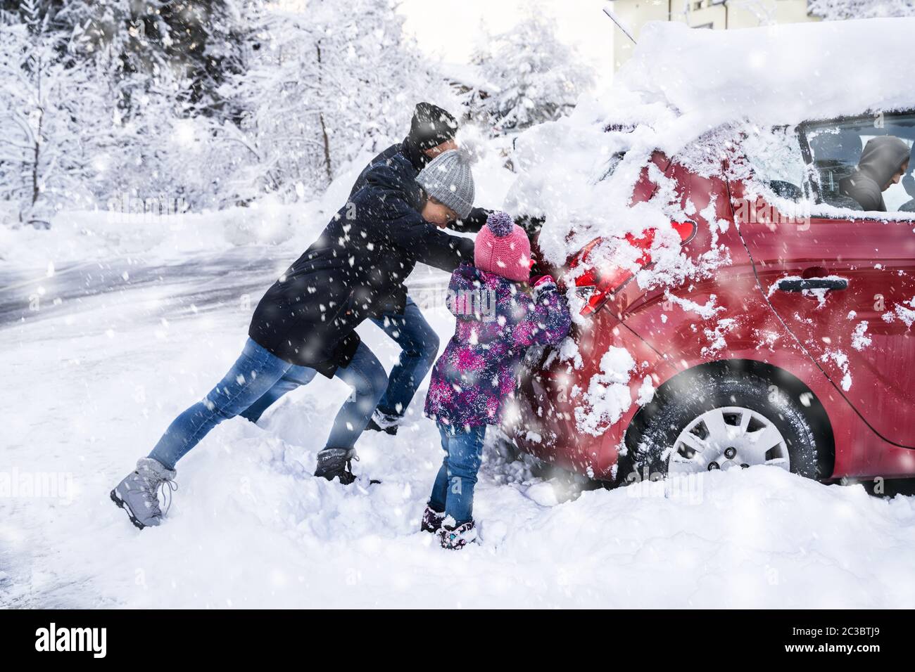 Famiglia spingendo una vettura bloccato nella neve dopo la nevicata Foto Stock